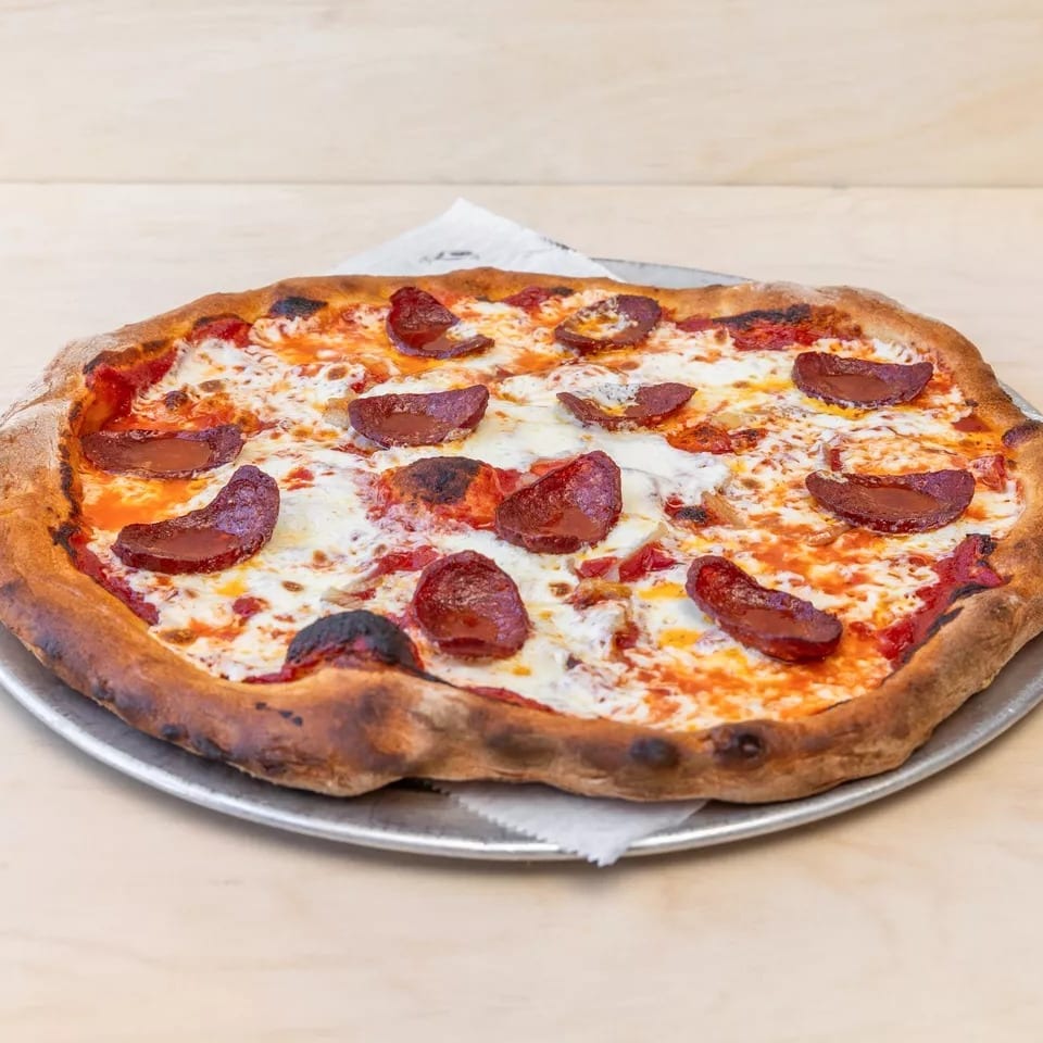 A whole pepperoni pizza with melted cheese and a crispy crust on a metal pan.